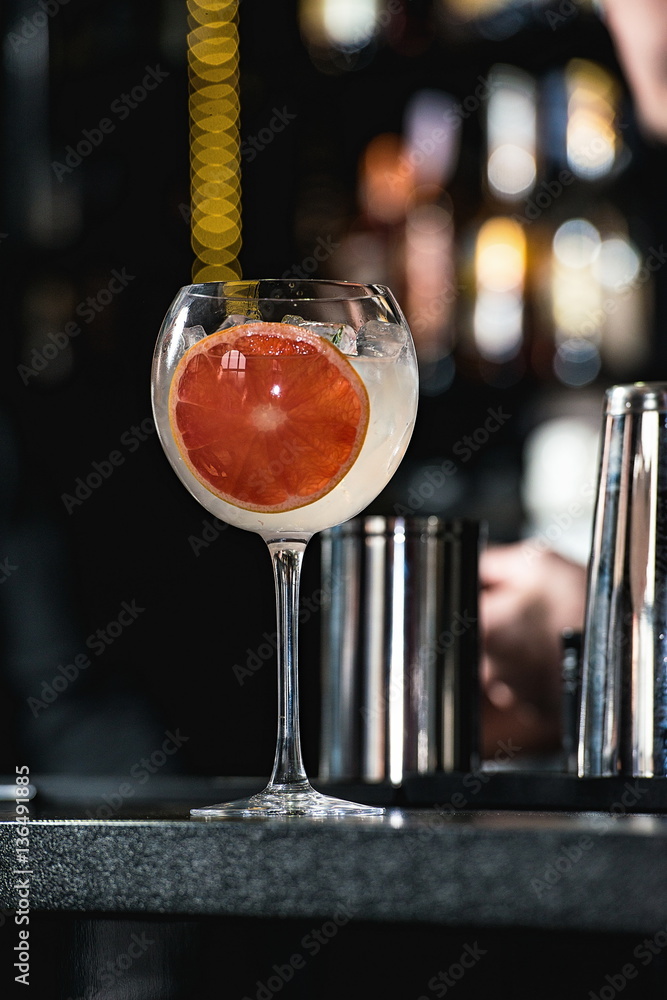 Wall mural refreshing ruby red coctail with grape fruit isolated on a bar b