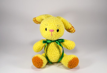 Knitted a plush yellow bunny with orange heels in a green ribbon. A toy. Gift. Handmade