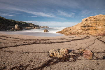 Waves wash onto a small sandy cove near Calvi in Corsica
