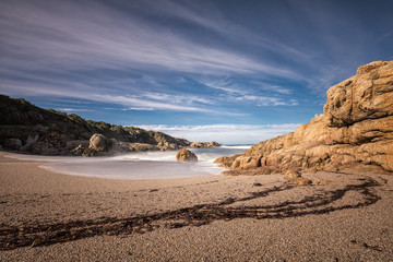 Waves wash onto a small sandy cove near Calvi in Corsica