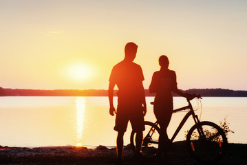 Fototapeta na wymiar couple on a bicycle at sunset by the lake