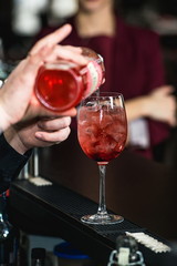 bartender making refreshing pink coctail with a rose on top isol