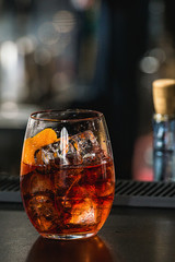 refreshing red coctail with orange isolated on a bar background