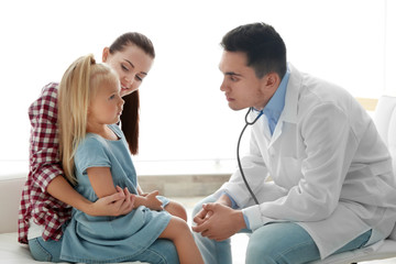 Fototapeta premium Male pediatrician doctor examining small girl