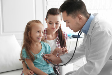 Male pediatrician doctor examining small girl