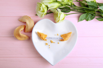 Plate with fortune cookie on wooden background