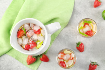 Jug with citrus cocktail and fresh fruits on light background, top view