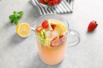 Jug with berry and citrus cocktail on light background