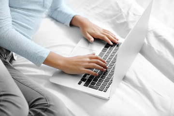 Cute girl lying on bed with laptop, closeup