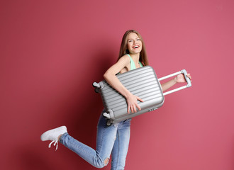 Woman traveler with suitcase on color background