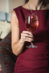 woman holds relaxing alcoholic pink coctail with a rose on top