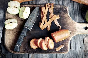 Cut carrots and sliced green apple on a kitchen board