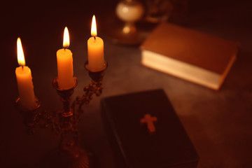 Burning candles with Bible on background