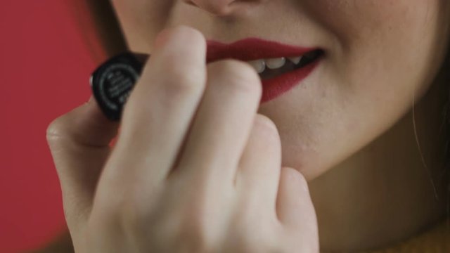 girl paints her lips close-up
