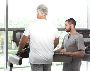 Rehabilitation concept. Mature man doing exercises under physiotherapist supervision