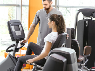 Rehabilitation concept. Young woman doing exercises under physiotherapist supervision