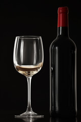 Bottle of wine and glass on black background