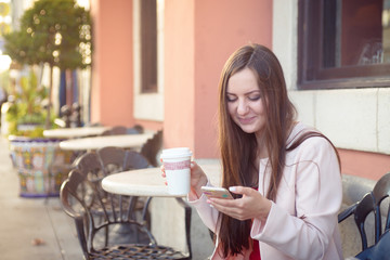 Young attractive woman smiling with mobile phone and cup of coffee