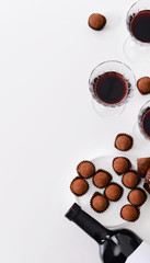 Obraz na płótnie Canvas Delicious chocolate truffles and red wine on white background