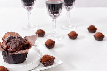 Delicious chocolate cake, truffles and red wine on white background