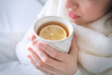 Young ill woman drinking hot tea with lemon at home, closeup - obrazy, fototapety, plakaty