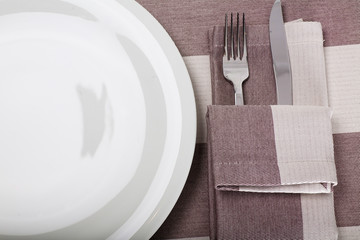 top view of empty plate, fork and knife on a linen tablecloth