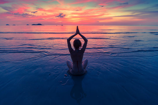 Meditation girl on the sea during sunset. Yoga silhouette.
