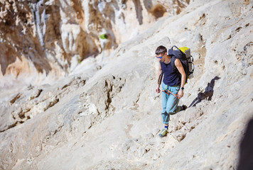 Rock climber in safety harness walking in climber sector