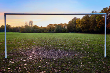 Soccer field at sunset in autumn or fall, mud and leaves on the ground