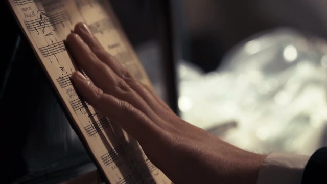 Pianist's hand holding the notes, that stand on the piano music stand