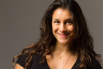 Fototapeta premium Young mixed race woman wearing a black t shirt and jeans stands in full face view while smiling at viewer