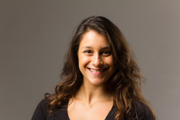 Obraz premium Young mixed race woman wearing a black t shirt and jeans stands in full face view while smiling at viewer