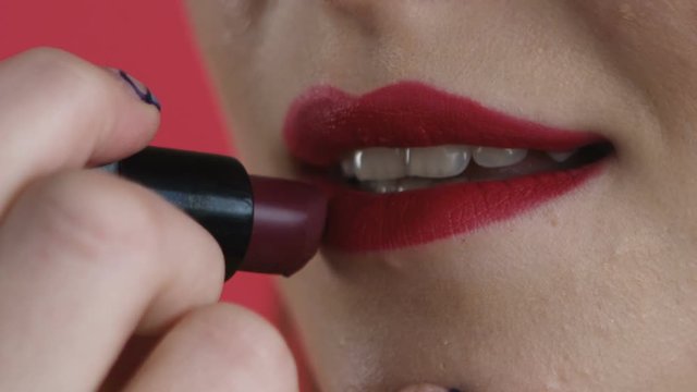 girl paints her lips close-up