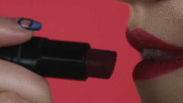 girl paints her lips close-up