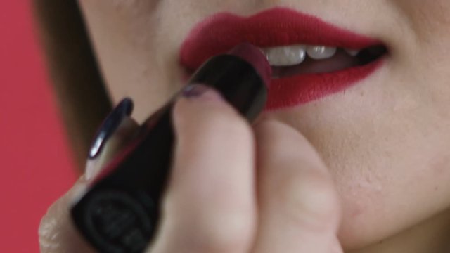 girl paints her lips close-up