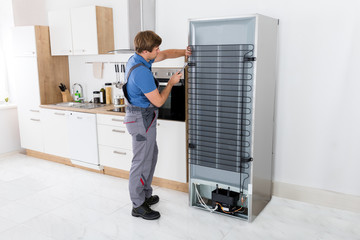 Serviceman Working On Fridge With Screwdriver