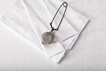 top view of a tea strainer on a white tablecloth
