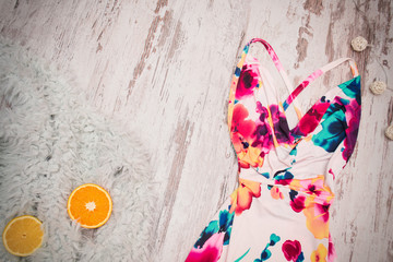 Bright summer dress and oranges on a gray faux fur, wood background. Fashionable concept, top view