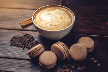 Coffee with macarons and chocolate in the shape of heart.