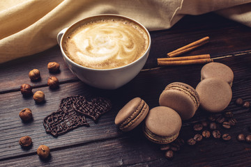 Coffee with macarons and chocolate in the shape of heart.