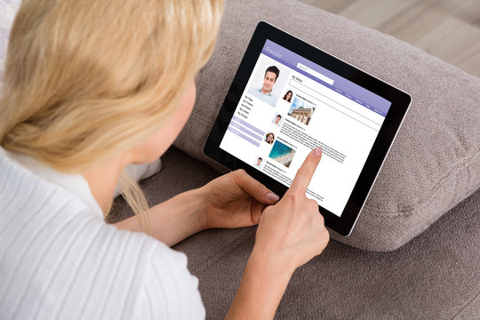 Woman Using Social Networking Site On Digital Tablet
