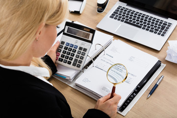 Businesswoman Calculating Invoice Using Calculator