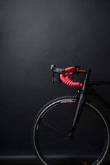 red handlebar and black wheel of a race bicycle on black backgro
