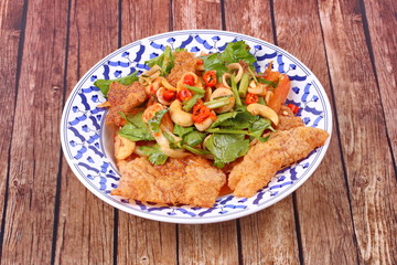 Spicy and sour mixed herb salad with crispy pork served .