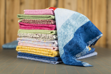 Stack of quilt material photographed edge on with a quilt block draped on top