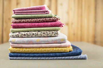 Stack of Fat Quarter quilt material oriented to the left of the image with no blue material behind