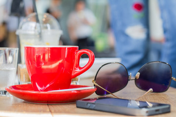 Red coffee cup with smart phone on wooden table