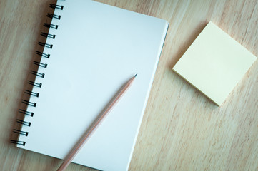 Notebook and pencil on wooden table.