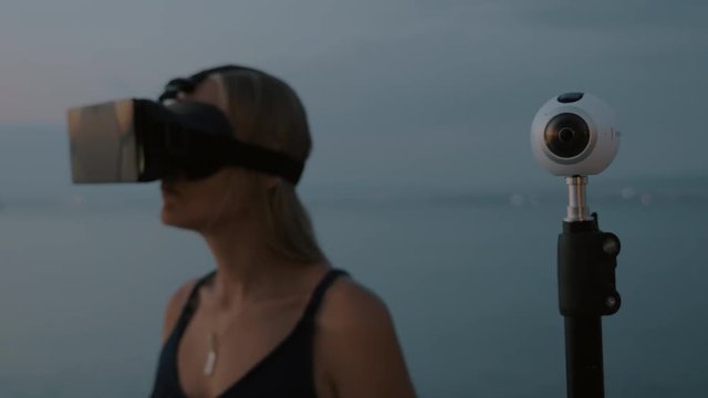 Shot with changing focus of a camera for 360 degree video and woman using VR-headset outdoor