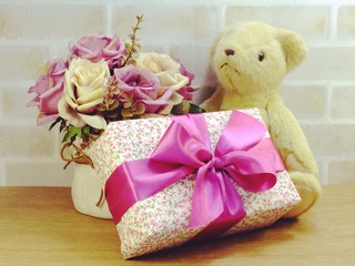 cute teddy bear doll with gift box and flowers with copy space